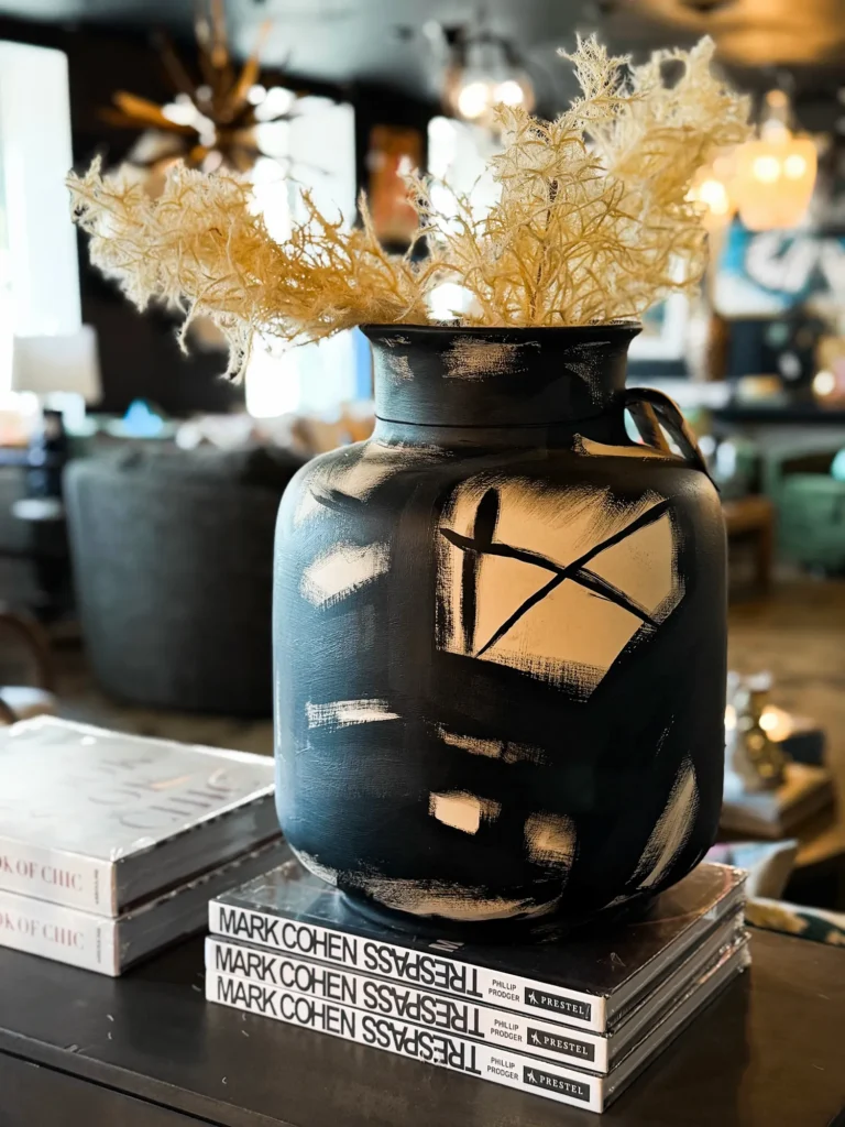 Black vase with dried florals styled on a stack of books