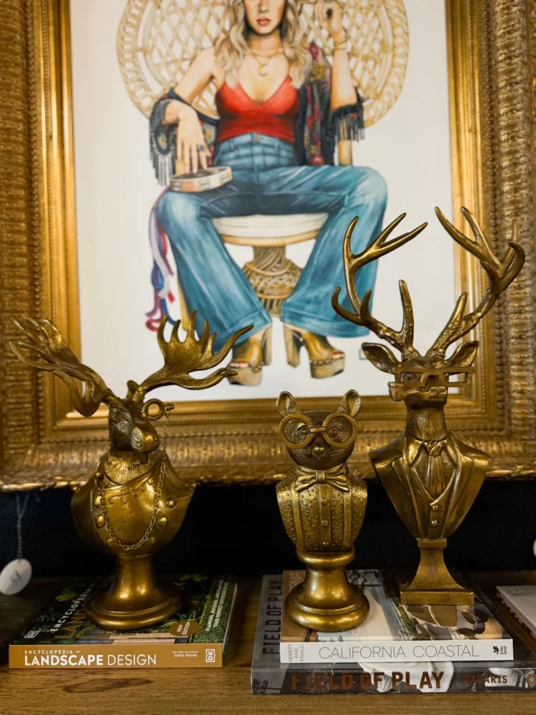 Brass deer figurines in front of colorful framed art