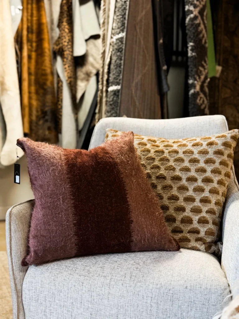 Burgundy and gold patterned throw pillows on a white chair