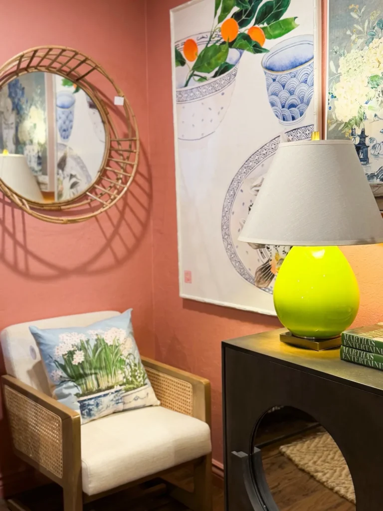 Lime green lamp, a rattan mirror and a cozy chair in a pink room vignette