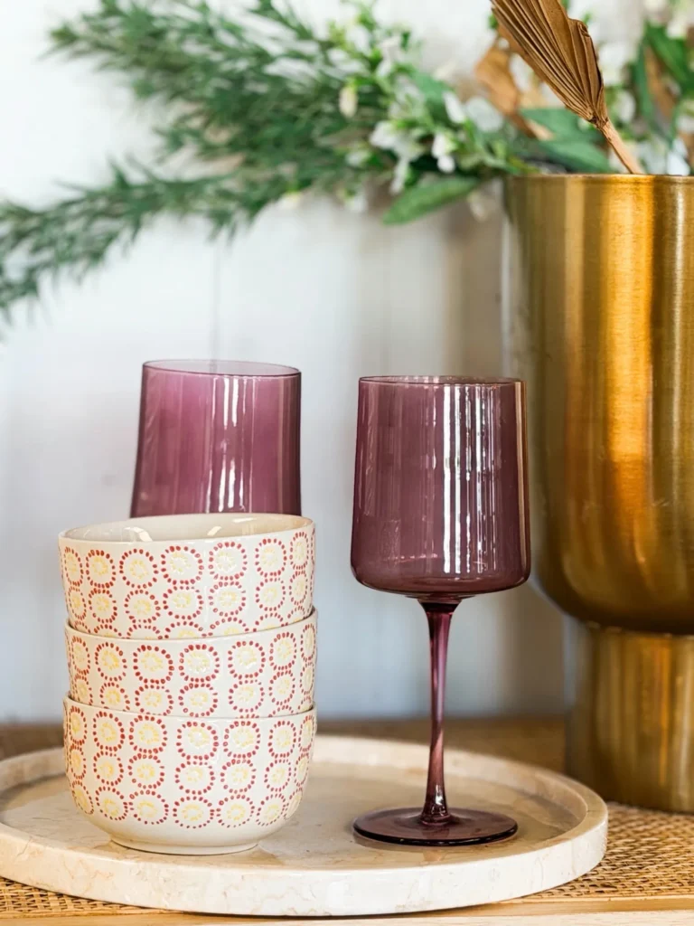Pink wine glasses and a candle styled with greenery