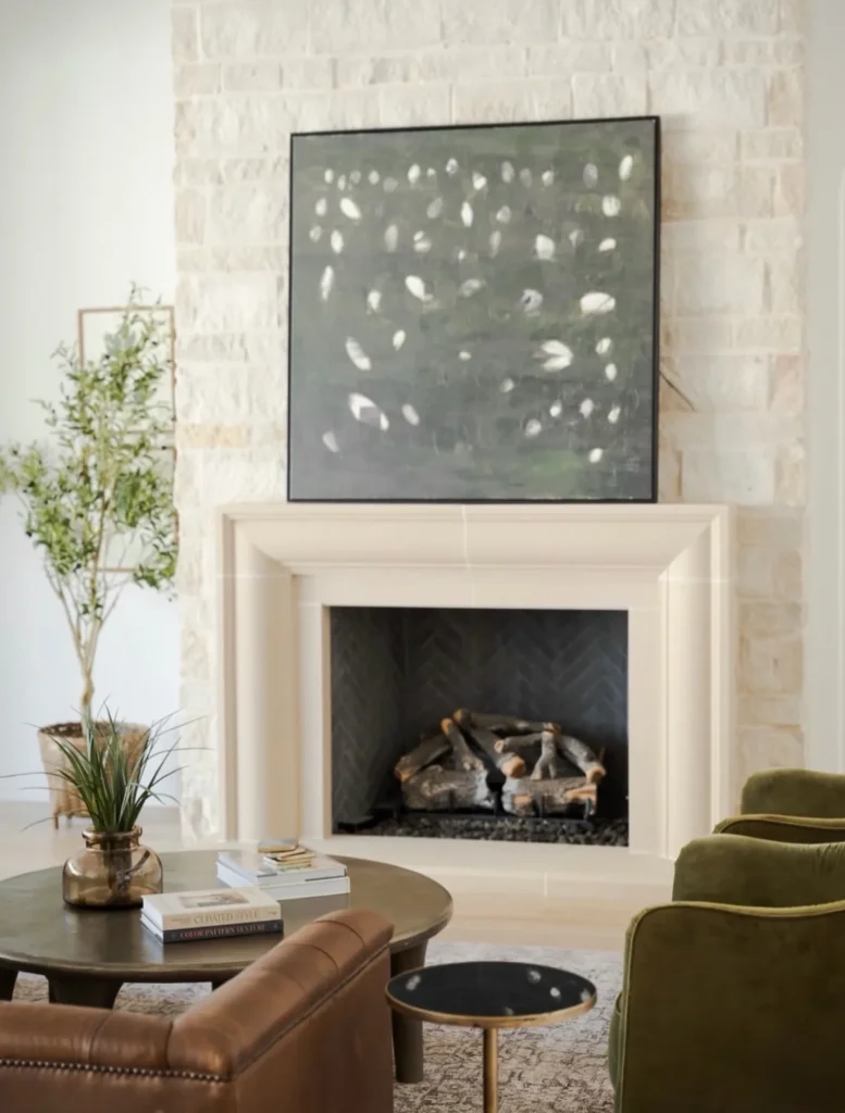 Staged living room with a limestone fireplace, abstract art and green chairs – home staging Oklahoma City by Live Boho