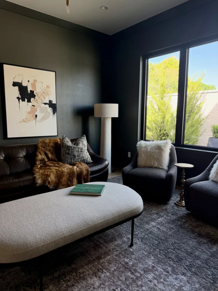 Moody staged lounge with dark walls, a round ottoman and abstract art – home staging Oklahoma City by Live Boho